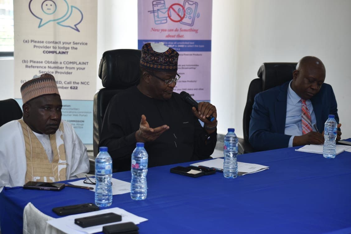 NCC officials seated at the head of the table, one gesturing while addressing the room