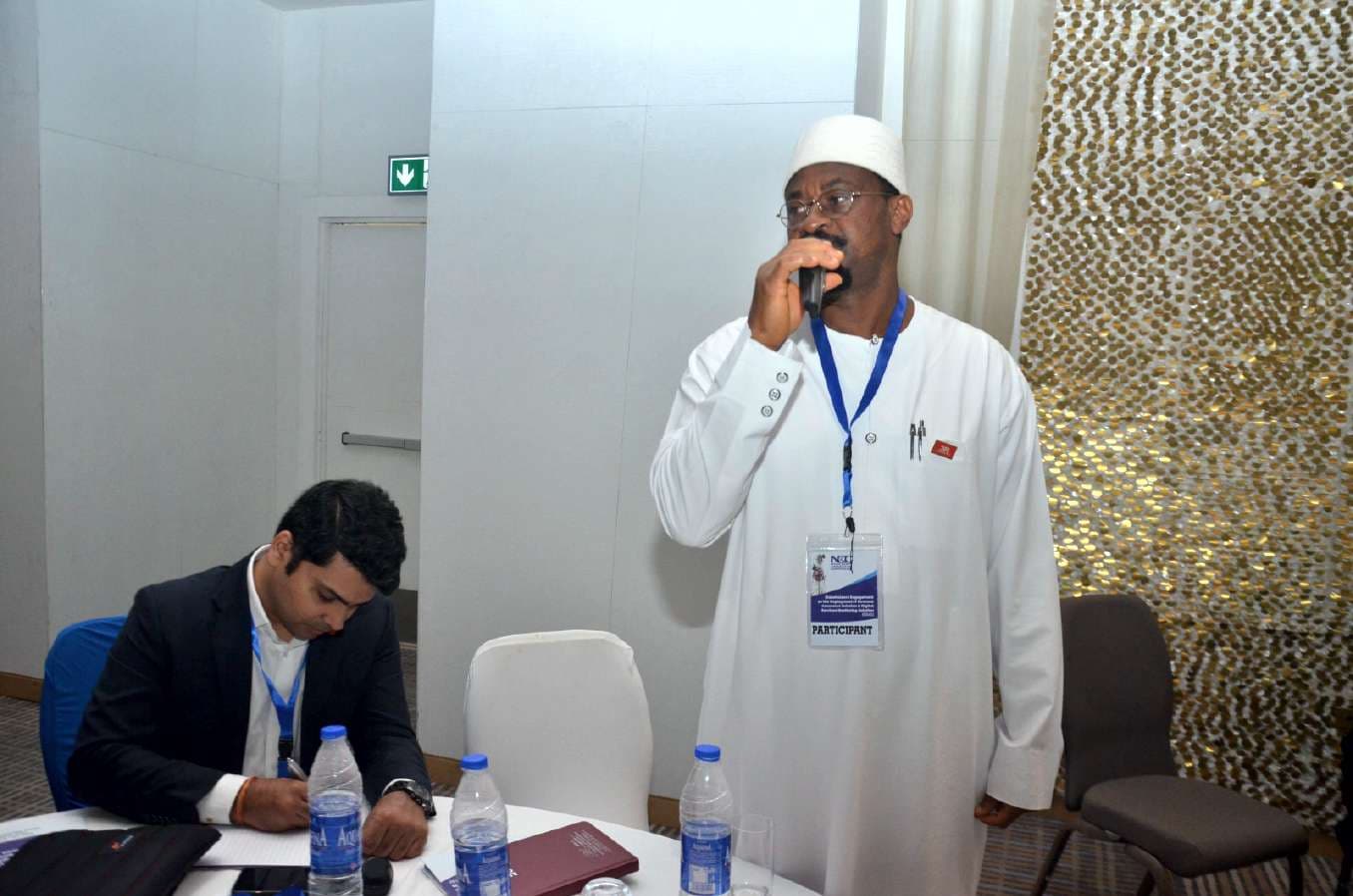 A participant sharing remarks into a microphone from his table during the engagement